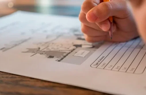A hand holding a pencil over a worksheet