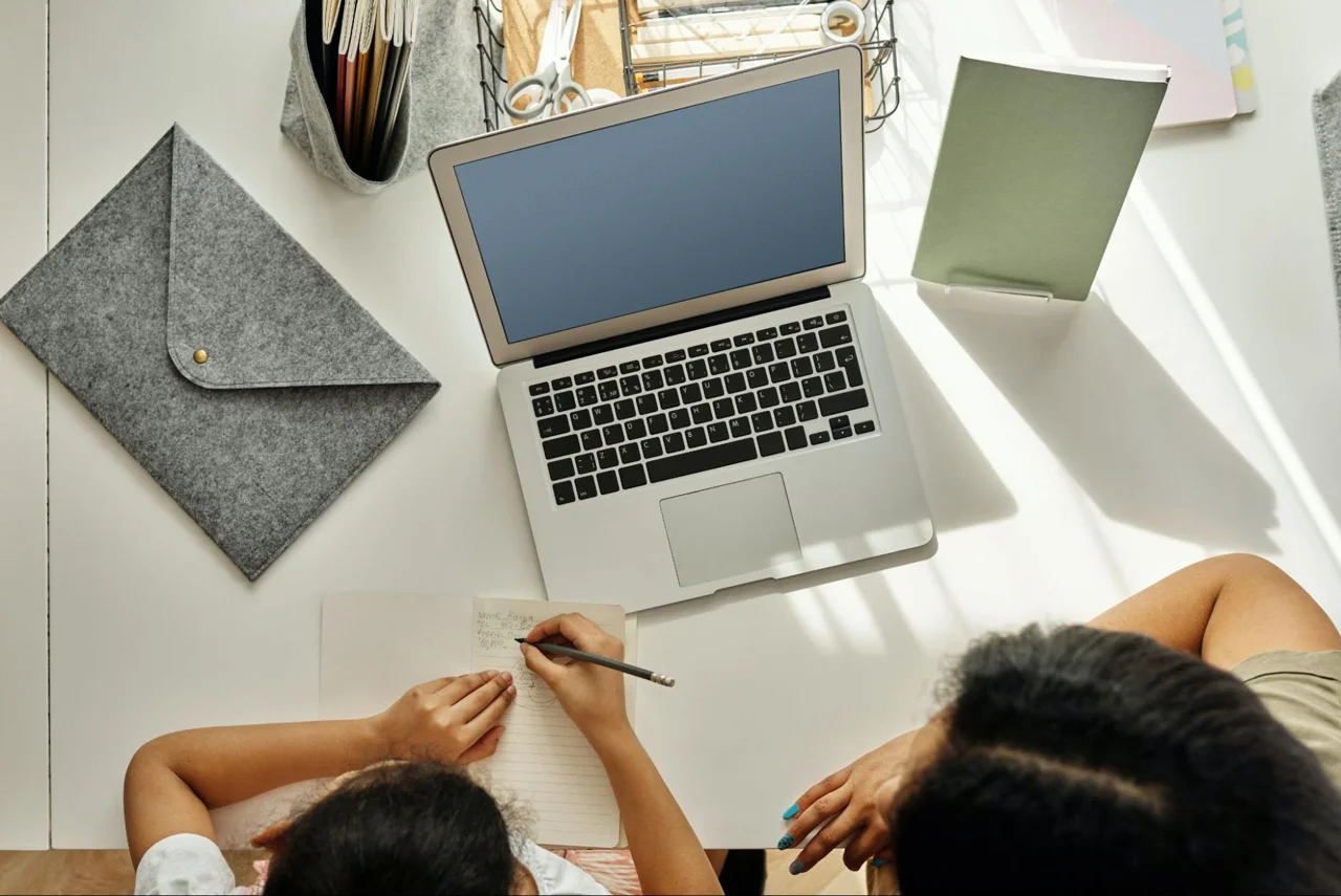Two people working with a notebook and laptop
