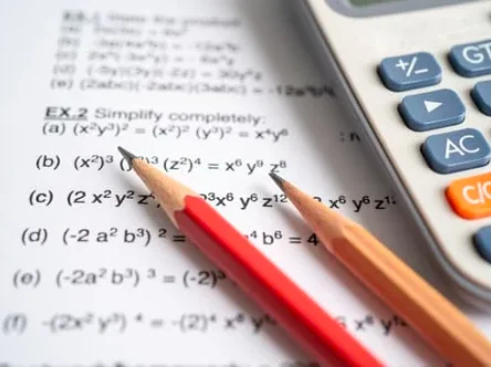 Pencils and a calculator beside mathematics exercises