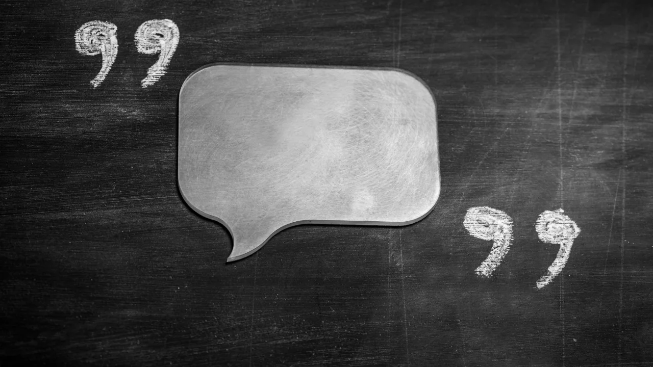 A speech bubble surrounded by quotation marks on a blackboard