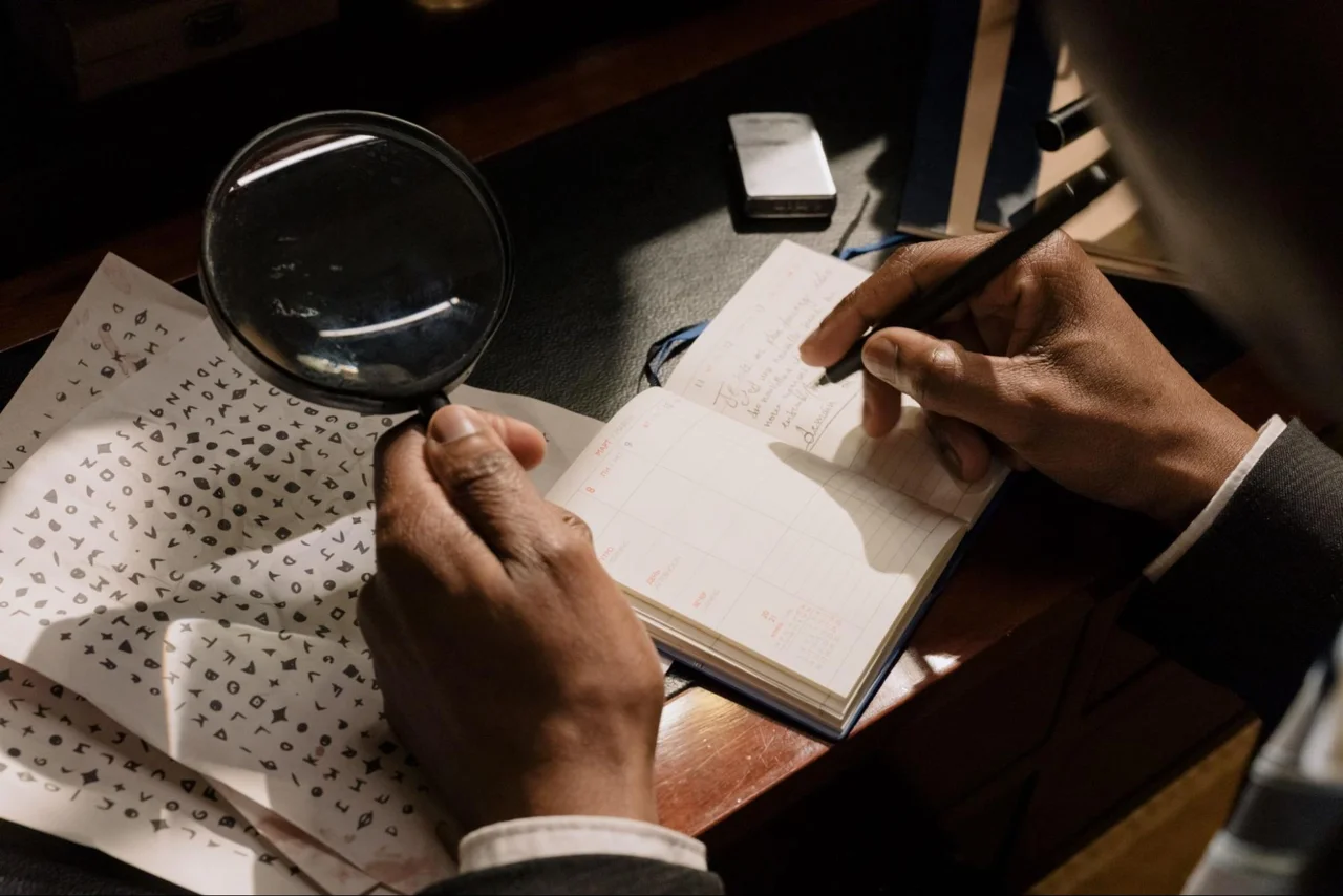 A person examining written material with a magnifying glass
