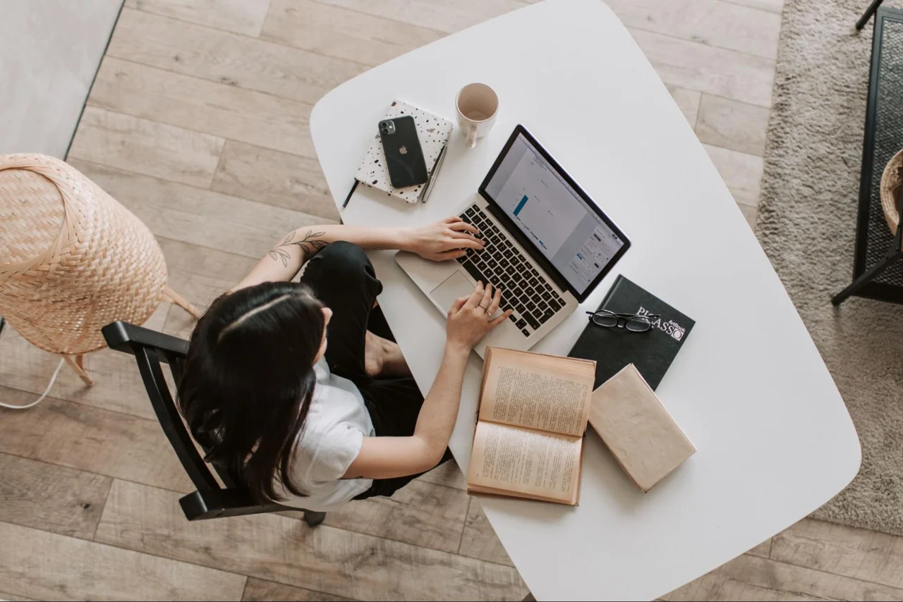 A reader studying with an open book and laptop